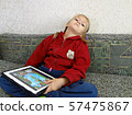 The girl with the tablet in her hands leaned back in the sofa. Photo expresses tired  57475867