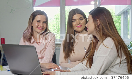 Lovely female college students laughing and talking at class, smiling to the camera Lovely female college students laughing and talking at class, smiling to the camera 57476406