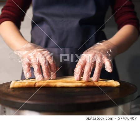 Chef making stuffed crepe, roll up crepe on hot cooktop. Step-by-step professional baking process Chef making stuffed crepe, roll up crepe on hot cooktop. Step-by-step professional baking process 57476407