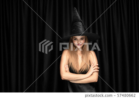 Young woman in hat as a witch on black background Young woman in hat as a witch on black background 57480662