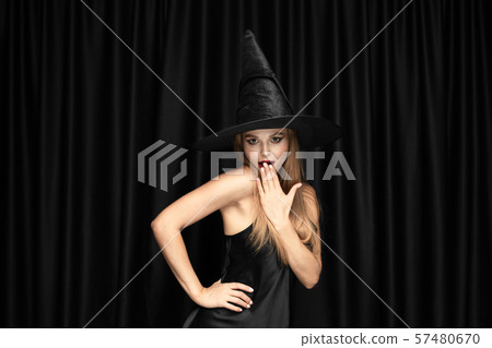 Young woman in hat as a witch on black background 57480670