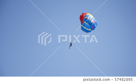 Man flying on parachute. In blue sky Man flying on parachute. In blue sky 57482895