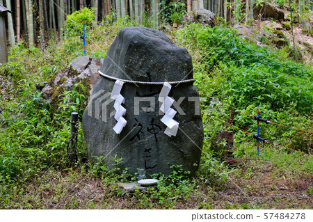 A monument written with a god of the mountain with a paper hanging on a rope. Located near the Nishiyama trailhead on the Kyoto Round Trail. 57484278
