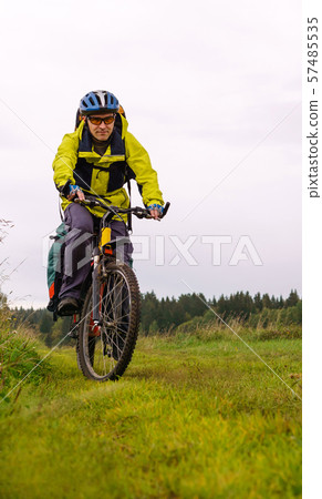 cycling tourist on a dirt road through a field cycling tourist on a dirt road through a field 57485535