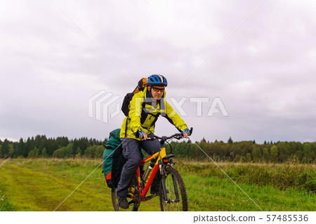 bikepacker rides on a dirt road through a field bikepacker rides on a dirt road through a field 57485536