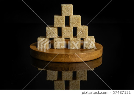 Brown sugar cube isolated on black glass Brown sugar cube isolated on black glass 57487131