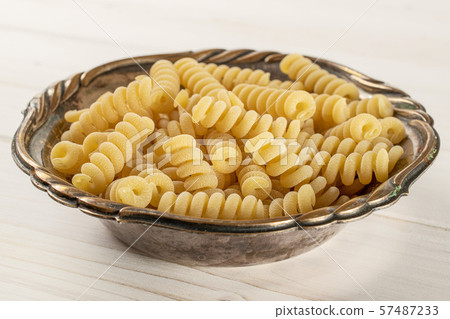 Raw pasta fusilli bucati on grey wood Raw pasta fusilli bucati on grey wood 57487233