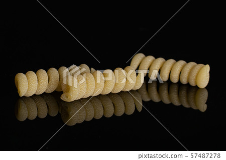 Raw pasta fusilli bucati isolated on black glass Raw pasta fusilli bucati isolated on black glass 57487278