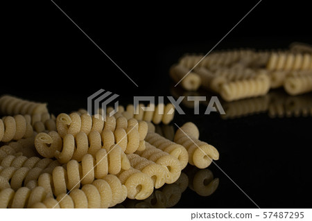Raw pasta fusilli bucati isolated on black glass Raw pasta fusilli bucati isolated on black glass 57487295