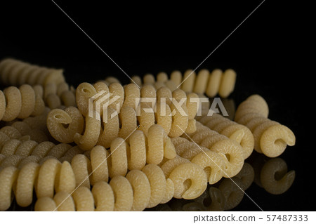 Raw pasta fusilli bucati isolated on black glass Raw pasta fusilli bucati isolated on black glass 57487333