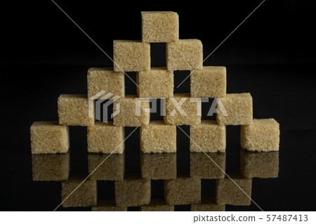 Brown sugar cube isolated on black glass Brown sugar cube isolated on black glass 57487413