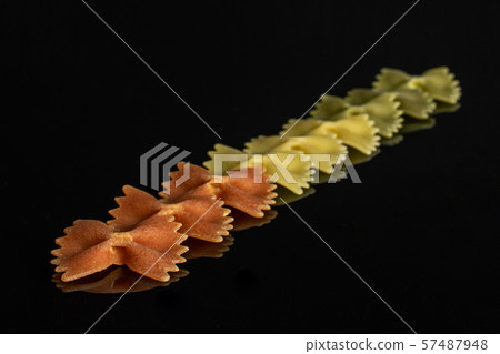 Raw farfalle tricolore isolated on black glass Raw farfalle tricolore isolated on black glass 57487948