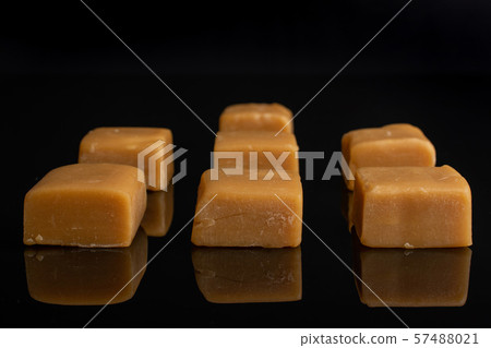Sweet caramel candy isolated on black glass Sweet caramel candy isolated on black glass 57488021