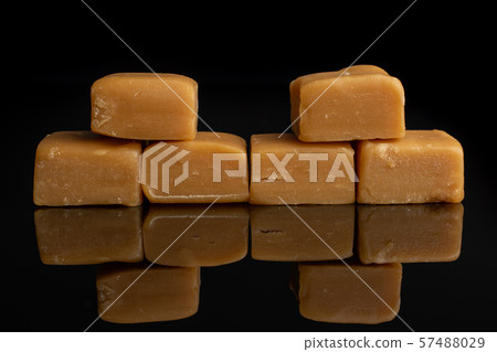 Sweet caramel candy isolated on black glass Sweet caramel candy isolated on black glass 57488029