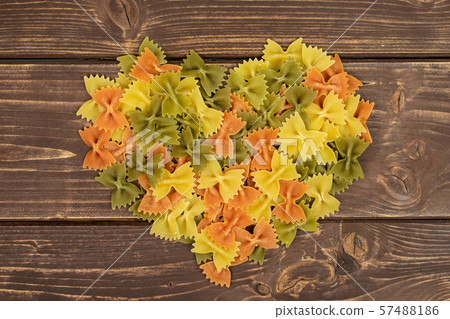 Raw farfalle tricolore on brown wood Raw farfalle tricolore on brown wood 57488186
