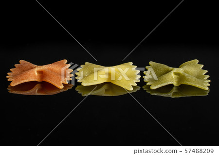 Raw farfalle tricolore isolated on black glass Raw farfalle tricolore isolated on black glass 57488209