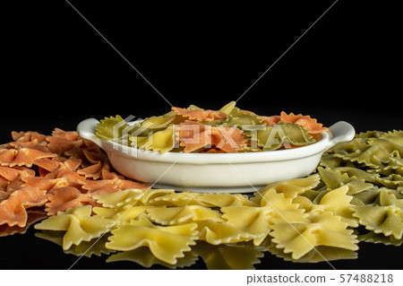 Raw farfalle tricolore isolated on black glass Raw farfalle tricolore isolated on black glass 57488218