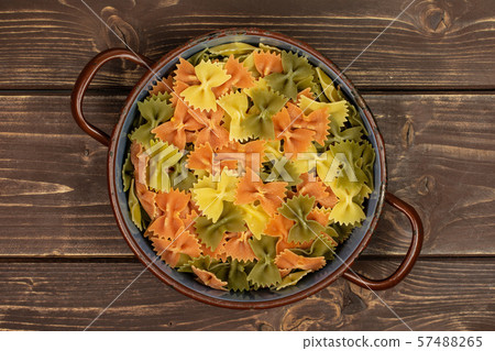 Raw farfalle tricolore on brown wood Raw farfalle tricolore on brown wood 57488265