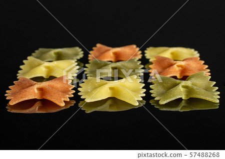 Raw farfalle tricolore isolated on black glass Raw farfalle tricolore isolated on black glass 57488268