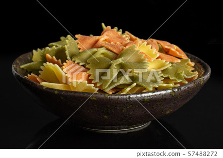 Raw farfalle tricolore isolated on black glass Raw farfalle tricolore isolated on black glass 57488272