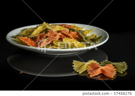 Raw farfalle tricolore isolated on black glass Raw farfalle tricolore isolated on black glass 57488276