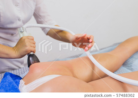 Cropped view of cosmetologist with roller doing buttocks starvac massage. Cropped view of cosmetologist with roller doing buttocks starvac massage. 57488302