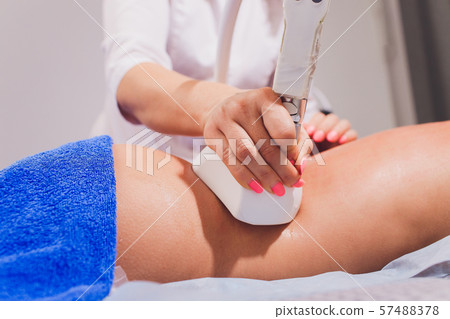 Cropped view of cosmetologist with roller doing buttocks starvac massage. Cropped view of cosmetologist with roller doing buttocks starvac massage. 57488378