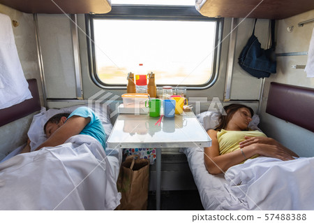 Man and woman sleep on lower shelves in a train Man and woman sleep on lower shelves in a train 57488388