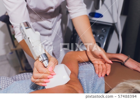 Cropped view of cosmetologist with roller doing buttocks starvac massage. Cropped view of cosmetologist with roller doing buttocks starvac massage. 57488394