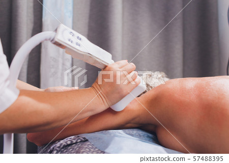 Cropped view of cosmetologist with roller doing buttocks starvac massage. 57488395