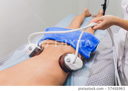 Cropped view of cosmetologist with roller doing buttocks starvac massage. 57488963