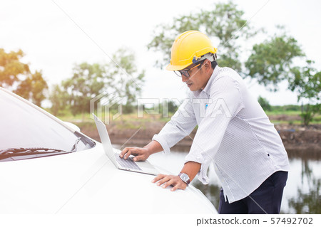 Asian Engineer yellow hat checking at site construction with laptop. Asian Engineer yellow hat checking at site construction with laptop. 57492702