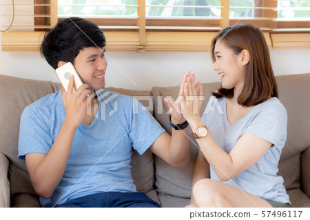 Beautiful young asian couple man and woman gesture high five together while man talking smart phone  57496117