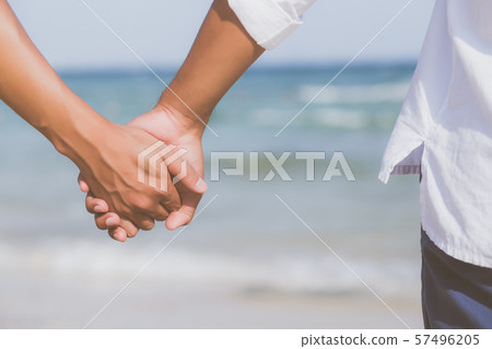 Closeup asian gay couple holding hands together on the beach with relax and leisure in summer Closeup asian gay couple holding hands together on the beach with relax and leisure in summer 57496205