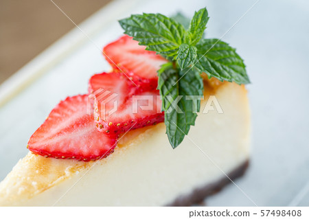 Piece of delicious cheesecake with strawberry and mint leaves on white plate. Piece of delicious cheesecake with strawberry and mint leaves on white plate. 57498408