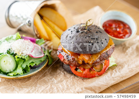 Cheeseburger with lettuce, tomato, fries, and melted cheese. The table in the restaurant. Unhealthy Cheeseburger with lettuce, tomato, fries, and melted cheese. The table in the restaurant. Unhealthy 57498459