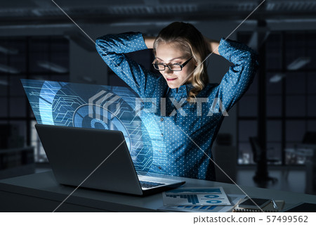 Beautiful blonde in dark office working on laptop and getting net access Beautiful blonde in dark office working on laptop and getting net access 57499562