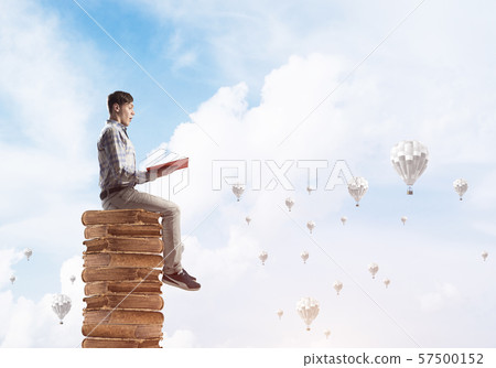 Man student on stack reading book and aerostats flying around Man student on stack reading book and aerostats flying around 57500152