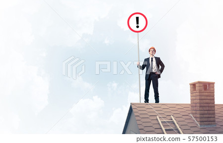 Businessman on house top showing sign with exclamation mark. Mix Businessman on house top showing sign with exclamation mark. Mix 57500153