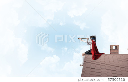 Girl power concept with cute kid guardian against cloudscape background. Mixed media Girl power concept with cute kid guardian against cloudscape background. Mixed media 57500510