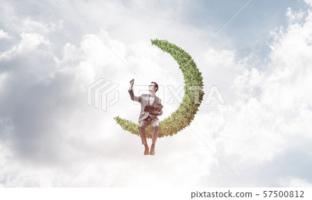 Young businessman or student on moon in sky studying the science 57500812