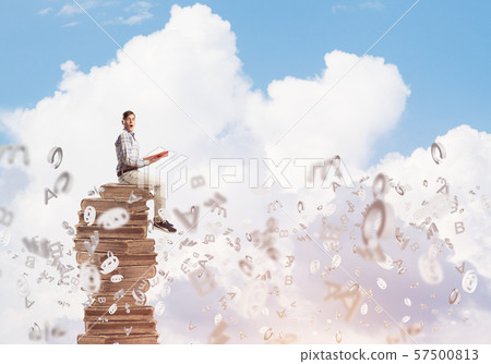 Man student on stack reading book and symbols flying around 57500813