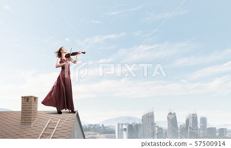 Woman violinist in red dress playing melody against cloudy sky. Mixed media 57500914