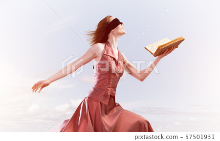 Girl against cloudy sky with opened book in palm as idea for knowledge 57501931