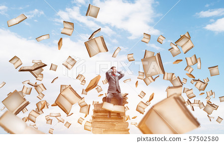 Young man on pile of books dont want to hear anything 57502580