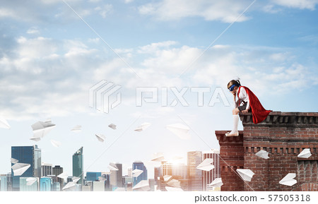 Girl power concept with cute kid guardian against cityscape background. Mixed media Girl power concept with cute kid guardian against cityscape background. Mixed media 57505318