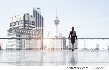 Sunrise above skyscrapers and businesswoman facing new day 57505912