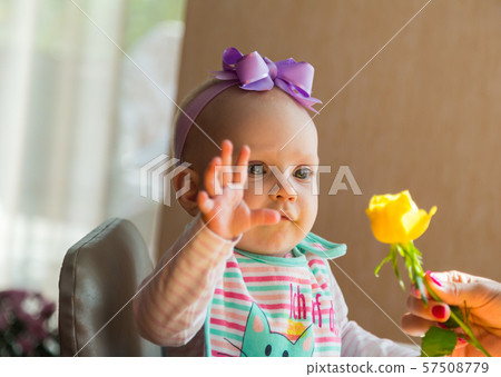 Baby rejoices in a flower 57508779