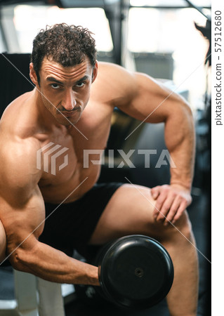 bodybuilder guy doing exercises with dumbbell.  57512680