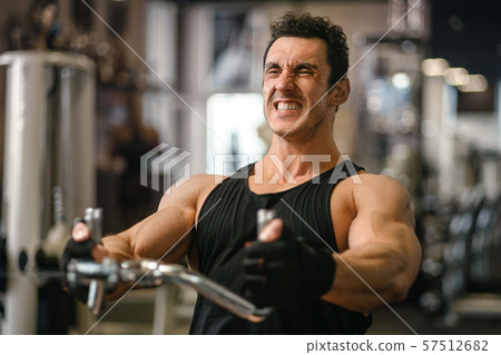 Man lifting weights at the cable machine in a gym. Man lifting weights at the cable machine in a gym. 57512682